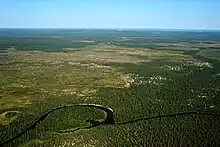 Paysage de toundra presque plar à perte de vue avec une méandre d'une rivière vue depuis un drone.