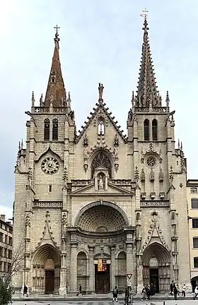 Photographie couleur montrant la façade d'une église, surmontée de deux flèches dissymétriques