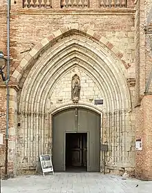 Portail du XIVe&nbsp;siècle avec dans le tympan une statue de St Francois