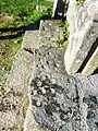 Cupules sur une dalle de schiste à l'entrée de l'enclos paroissial, traces probables d'un culte préchrétien