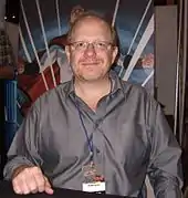 photo en couleur rapproché taille de Mark Waid assis derrière une table