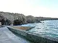 Falaises et grottes au sud-est du petit port de Cameros (situé au premier plan) à marée haute.