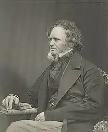 Gravure d'un homme aux cheveux mi-longs bouclés avec des favoris portant un costume et assis la main sur un livre
