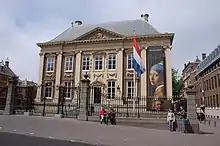 Vue de la façade du musée portant une affiche géante de La Jeune Fille à la perle.