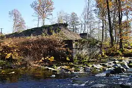 Des talus noirs dépassent d'un bloc de béton derrière un court d'eau.