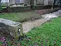 Saint-Thuriau : le ruisseau de la Fontaine Névé en période de fortes pluies à proximité de la chapelle de Gohazé et juste avant sa confluence avec le Blavet. Le cercle sur le muret indique le niveau atteint par l'eau lors de la crue du Blavet en janvier 2001.