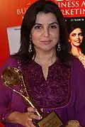 Portrait de Farah Khan, tenant un trophée dans les mains.