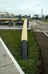 Après avoir fait un angle droit, un tuyau de couleur beige s'enfonce dans la terre.