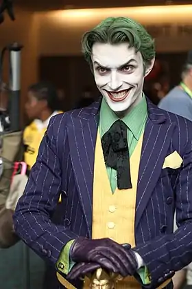 Photo en buste d'un homme déguisé en Joker, avec un sourire machiavélique.