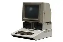 Ordinateur gris équipé d'un clavier, de deux lecteurs de disquette et d'un petit moniteur.