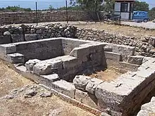 photographie : ruines de murs formant un bâtiment rectangulaire divisé en son milieu