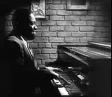 Un pianiste noir est assis à son piano.