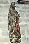 Photographie d’une statue de saint Luc rédigeant l’évangile, en bois sculpté du XVIIe siècle.