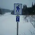 Un panneau de signalisation blanc montrant un randonneur et l'inscription SIA/IAT