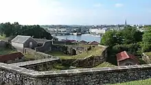 Vue en surplomb de remparts dominant un cours d’eau.