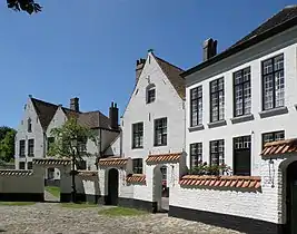 Maisons no&nbsp;16 (à droite, millésimé 1854 en façade), no&nbsp;18 (au centre, XVIe et XVIIe&nbsp;siècles) et no&nbsp;20 (double pignon de gauche, également des XVIe et XVIIe). Le mur de séparation entre jardinets des maisons et enclos central est bien visible.
