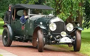 Photo d'une voiture verte avec une carrosserie découvrable et la capote relevée.