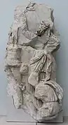 homme barbu bras levé devant une statuette