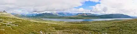 Un lac entouré de montagnes, sous un ciel nuageux.