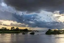 Nuages bleus et orange au-dessus du Mékong avec une pirogue filant sur l'eau au coucher du soleil à Don Det. Juillet 2020.