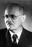 Photo en noir et blanc d'un homme à lunettes rondes.