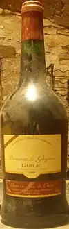 La photo couleur représente une bouteille couverte de poussière révélant don vieillissement.