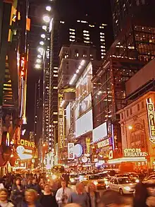 Grand boulevard de nuit avec des personnes et des voitures.