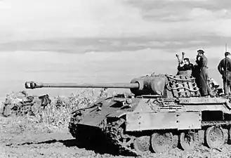 Photographie montrant un Panther à l’arrêt vu de profil avec son équipage debout à l’arrière de la caisse et le commandant émergeant de la tourelle.