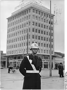 photographie noir et blanc : un policier casqué devant un immeuble moderne