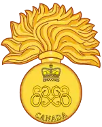 Image en couleur d'un insigne militaire composé d'une grenade allumée de 17 flammes avec deux monogrammes des lettres « ER » affrontés au centre ainsi qu'une couronne royale au-dessus et le mot « Canada » en dessous ; le tout est de couleur dorée.
