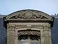 Lettres O et G au fronton d'une fenêtre.