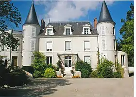 Photographie en couleurs d'un château de deux étages, le toit étant en ardoises et les combes aménagées ; flanqué de part et d'autre de deux tours.
