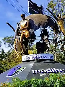 Une statue en métal représentant un globe dont sortent plusieurs personnes qui courent en portant des torches ou en levant les bras.