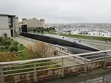 Vue panoramique du sous-marin dans sa darse avec en arrière-plan le bâtiment du musée