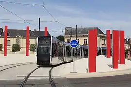 Une rame de tramway quittant la station Tranchée, passe entre les colonnes rouges de Daniel Buren.