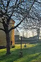 Vue prise depuis l'intérieur de la cour du Châteauneuf-sur-Epte. Cerisier en fleurs au premier plan, le pigeonnier et les communs en arrière-plan. Printemps, début de journée.