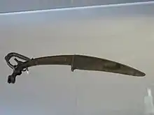 Couteau xiao à tête de bouquetin ibex. Nord ou Nord-Ouest de la Chine trouvé au Shanxi. Bronze. XIIIe – XIe&nbsp;siècle&nbsp;av. J.-C.. Musée Cernuschi