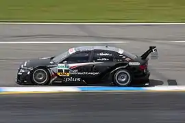 Voiture noire, de profil, sur une piste sèche.