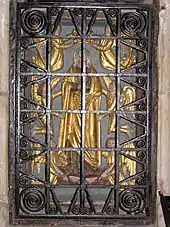 Photographie d'un bas-relief en partie doré derrière une grille