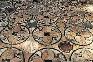 Un autre pavement moins bien conservé à Ostie. On y voit du marbre jaune antique, du blanc veiné, du porphyre vert (fines bordures), du porphyre rouge et du granite gris (quelques disques).