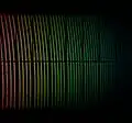 Spectre de la première lumière d'ESPRESSO. Cette vue a été colorisée pour indiquer comment les longueurs d'onde changent à travers l'image, mais ce ne sont réellement pas les couleurs qui seraient vues visuellement. De nombreuses lignes spectrales sombres sont visibles dans le spectre stellaire, ainsi que les doubles points réguliers d'une source de lumière d'étalonnage. Les bandes noires sont dues à la façon dont les données sont prises et ne sont pas réelles.