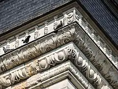 Vue rapprochée du décor sculpté de la corniche moulurée.
