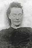 Photographie mortuaire en noir et blanc d'une femme présentant des traits anguleux et une grande bouche.