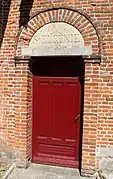 Porte latérale avec une imposte en pierre sculptée "Sainte-Eugénie".