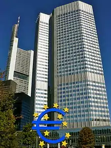 Gratte-ciel de l'Eurotower, 40 étages ; d'autres grattes-ciel plus petits sont visibles sur la gauche. En bas de la tour, une sculpture bleue du symbole de l'euro autour et dans lequel se trouvent onze étoiles jaune.