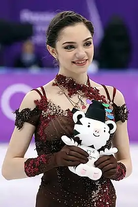Une femme une robe rouge avec des fleurs, tenant une peluche de tigre blanc.