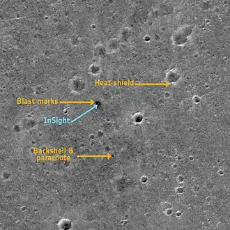 Cette image panchromatique montre le site d'atterrissage d'InSight sur Mars. Elle a été prise par l'instrument CaSSIS (Colour and Stereo Surface Imaging System) du satellite ExoMars Trace Gas Orbiter, issu de la collaboration entre l'Agence spatiale européenne et Roscosmos, le 2 mars 2019. L'image montre une surface de plus ou moins 2,25&nbsp;km x 2,25&nbsp;km dans la zone Elysium Planitia.