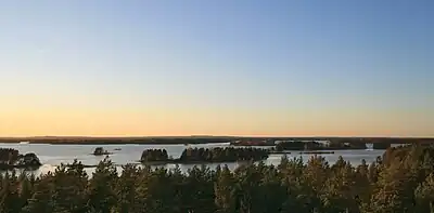 Coucher de soleil sur un grand lac avec des îlots boisés.