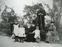 Famille posant avec parents et enfants, tous en tenue du XIXe siècle.