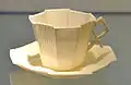 Tasse aux rebords anguleux sur sa soucoupe.